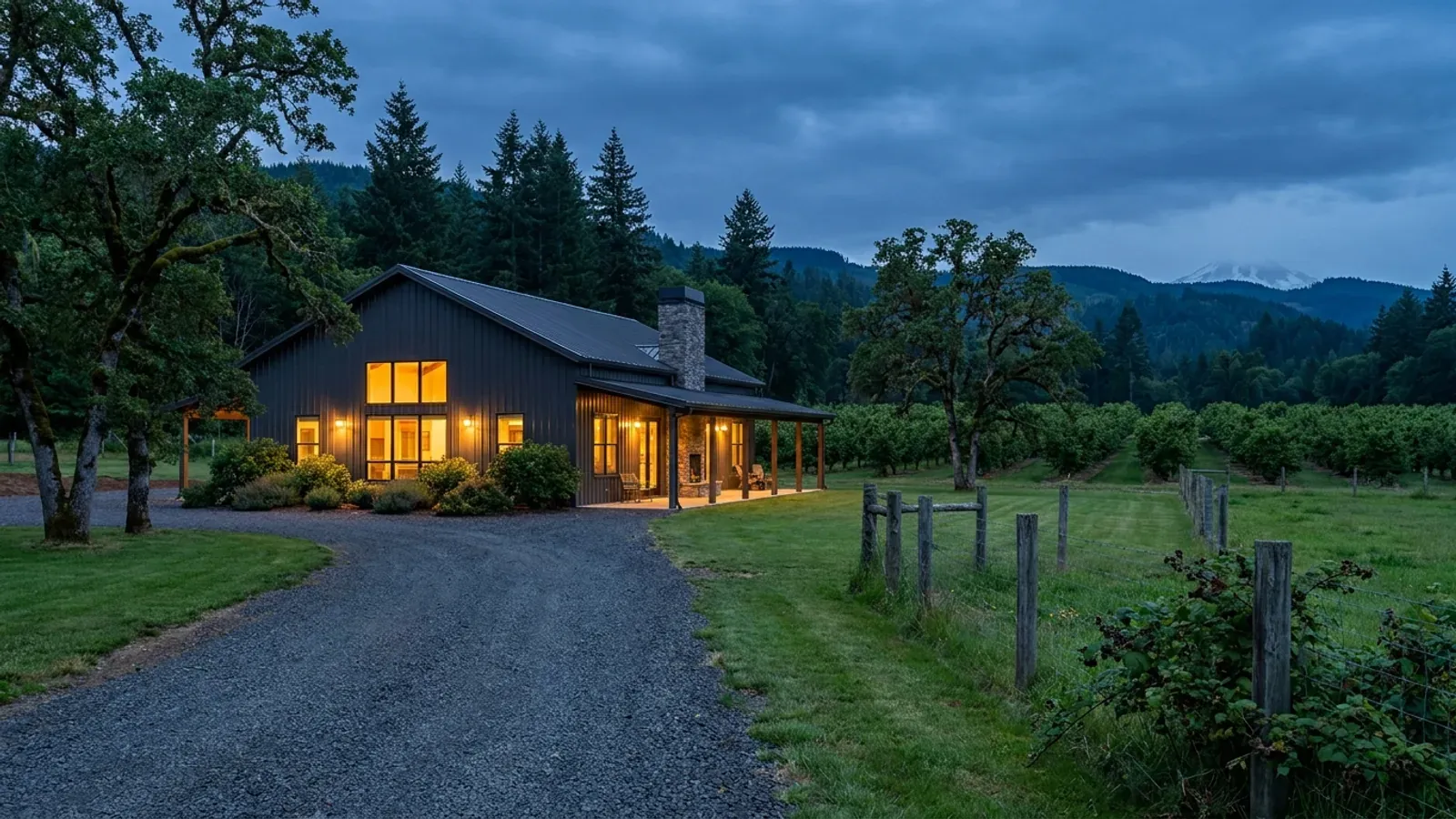A finished barndominium at dusk with warm interior lighting glowing through its large windows.